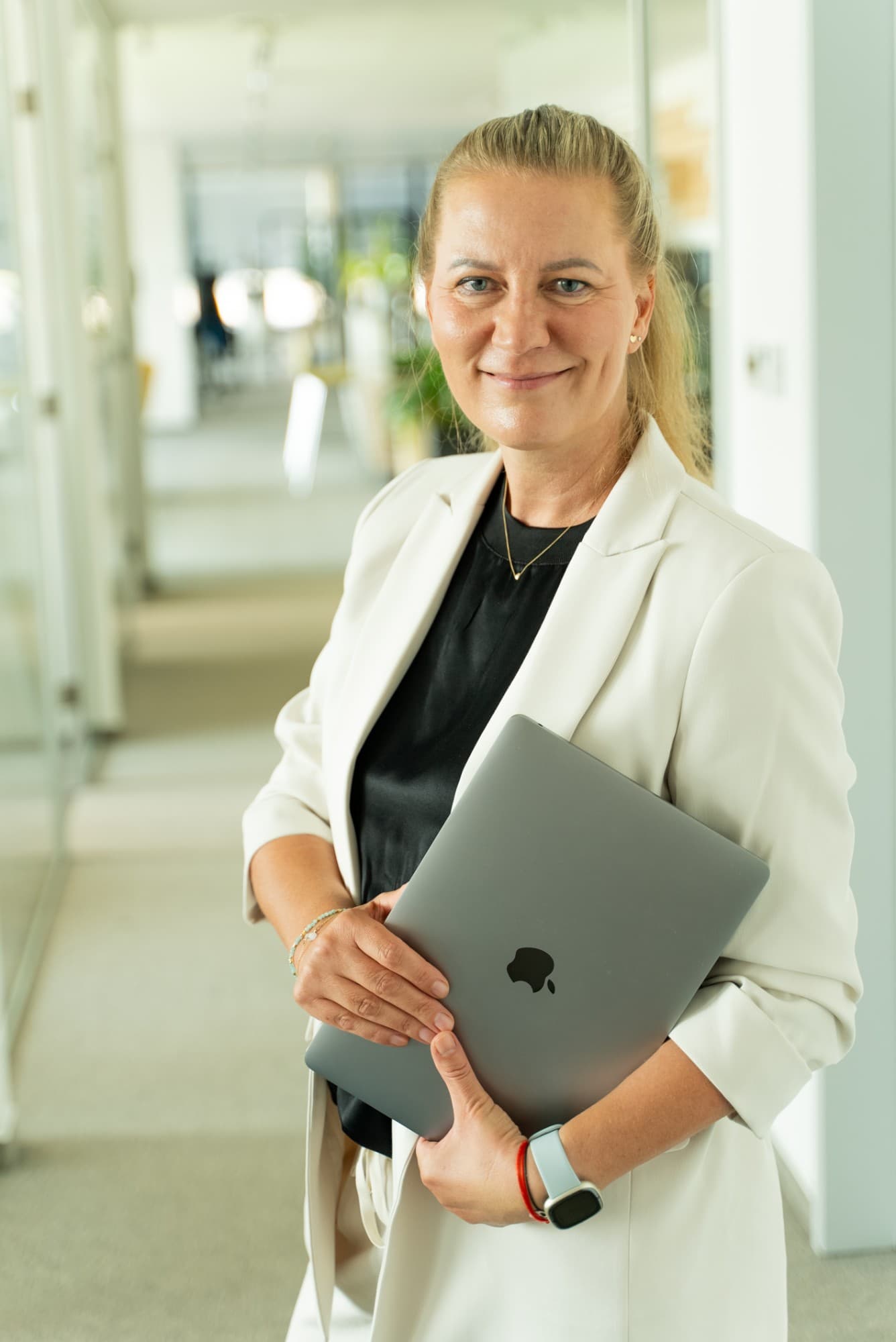 Erika Heveši v bielom saku s notebookom v kancelárii